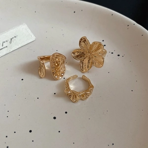 Detailed view of three gold flower rings with organic textures on a ceramic tray