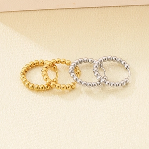 Detail of small 18K gold and silver hoop earrings with unique beaded texture on fabric