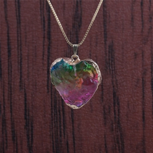 Close-up of heart-shaped colorful crystal pendant with gold rim on a metal chain