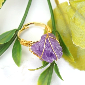 Detailed shot of handmade gold wire wrapped purple raw stone ring with adjustable band
