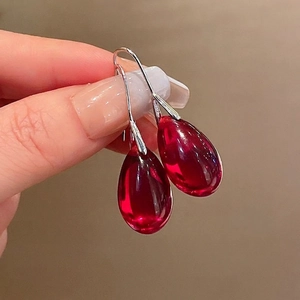 Dettaglio dei orecchini a goccia in resina rossa con ganci in argento fatti a mano