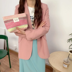 Model holding a colorful striped woven makeup bag with vibrant pink and beige patterns