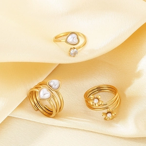 Close-up of 18k gold-plated rings with pearls and heart patterns on yellow satin cloth