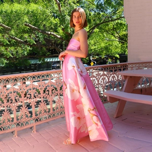 Detail eines rosa Satin-Trägerkleids mit großen weißen Blumenprints im Außenbereich