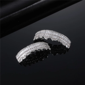 Iced out silver hip hop grillz set with baguette and round cut zircons on black surface