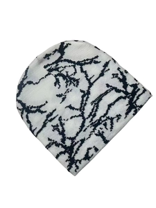 Detailed top view of black and white knitted beanie with branch texture on white background