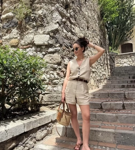 Close-up of beige linen vest and high-waisted shorts set with a brown leather belt