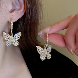 Detail of butterfly drop earrings with zircon stones on a model, elegant silver finish