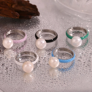Five colorful enamel stainless steel rings with white beads on a wet mirror surface