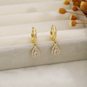 Detailed view of elegant gold teardrop hoop earrings with pavé crystals in a jewelry box