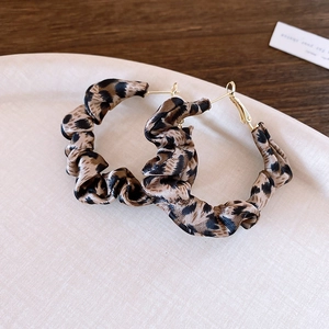 Close-up of leopard print fabric-wrapped hoop earrings with golden studs on a tray