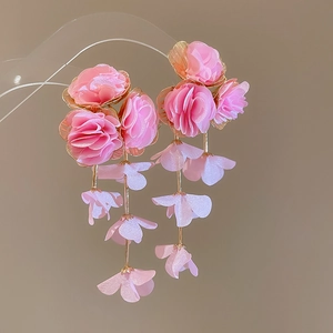 Detailed view of pink chiffon flower tassel earrings with metal petals on clear stand
