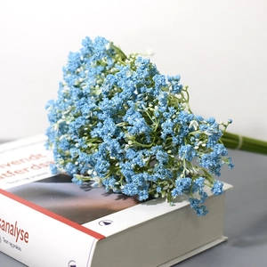Detailed close-up of blue artificial baby's breath bouquet on a white book