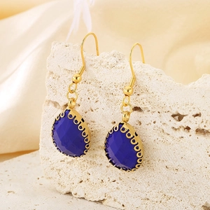 Macro de boucles d'oreilles goutte en verre bleu sur pierre naturelle et tissu en soie
