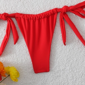 Dettaglio slip bikini rosso con laccetti laterali regolabili e vita elastica arricciata