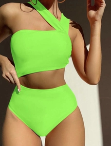 Detail of neon green one-shoulder swimsuit featuring waist cut-out and high-waisted design