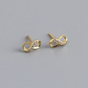 Macro shot of gold infinity symbol stud earrings with shimmering small clear gemstones