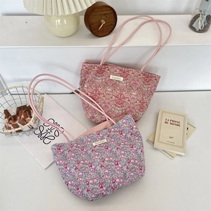 Détail de sacs fourre-tout en toile à fleurs avec fines bandoulières et étiquette tissée