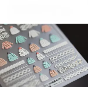 Detailed view of 3D embossed winter sweater textures and knitted hat nail art stickers