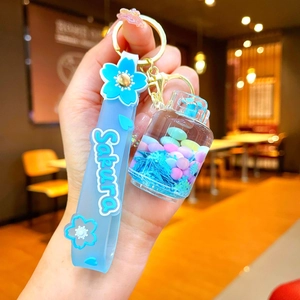 Close-up of Sakura liquid glitter keychain with blue silicone wristband and floral charms