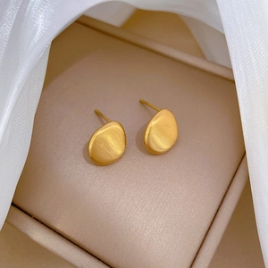 Macro shot of gold oval stud earrings with brushed metal finish in a jewelry box