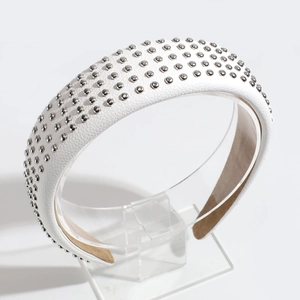 Close-up of white leather headband with silver rivet studs on clear display stand