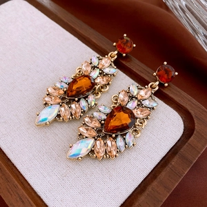 Detailed shot of vintage gold drop earrings with amber and champagne crystals on wood