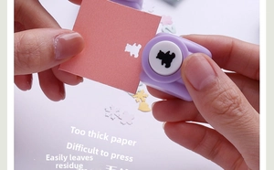 Manual craft punch tool showing hand pressing process to create bear patterns on paper