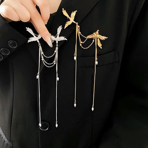 Detail of bird brooch with golden and silver tassels and pearls on black suit jacket