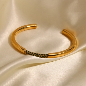 Dettaglio bracciale in acciaio inossidabile oro 18K con zircone verde su seta avorio