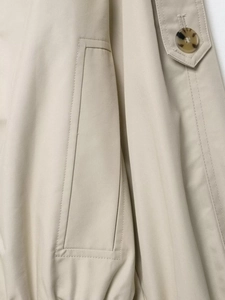 Detailed close-up of khaki waterproof windbreaker with amber button and twill texture