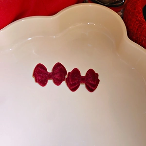 Close-up of elegant wine red velvet bow earrings on a cloud-shaped display tray