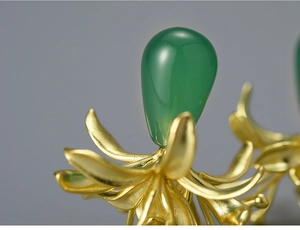Macro detail of green chalcedony teardrop stone on gold lycoris flower earring
