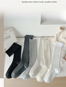Detail of ribbed knit knee-high socks in black, grey, beige, and white solid colors