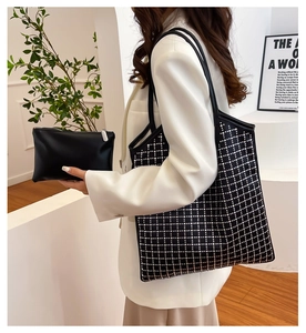 Detail of black rhinestone grid tote bag with small leather clutch shown on a shoulder