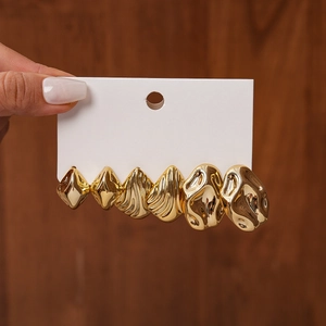 Close-up of gold geometric earring set with textured oval and irregular folded designs