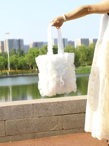 Outdoor shot of white ruffled mesh tote bag with tiered tulle design by a lake