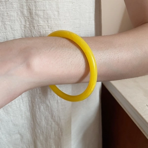 Close-up of a translucent yellow resin bangle on a wrist with minimalist design