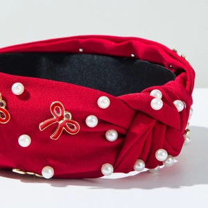 Detail of red knotted headband with pearls and red enamel butterfly charm decoration