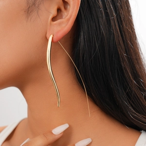 Close-up of golden teardrop metal earrings worn by a model for a minimalist fashion look