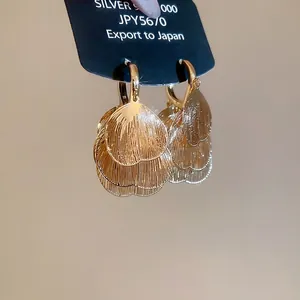 Golden layered petal heart hoop earrings with brushed texture on black card