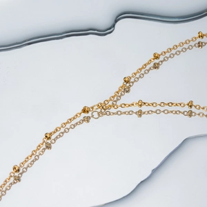 Minimalist 18k gold plated stainless steel bead chain bracelet on a mirror surface