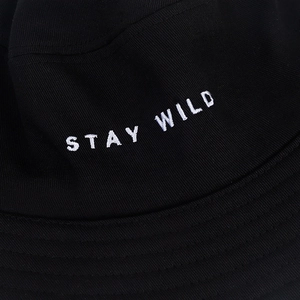 Gros plan sur la broderie blanche 'STAY WILD' du bob en coton sergé noir de haute qualité