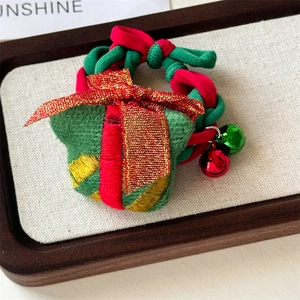 Detail of Christmas scrunchie with green gift box decor, glitter bow and metal bells