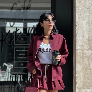 Detail of burgundy zipper jacket with collar and matching drawstring shorts in street style