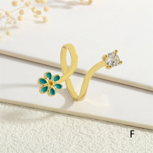 Detail of gold open ring featuring a blue enamel flower and sparkling zircon stone