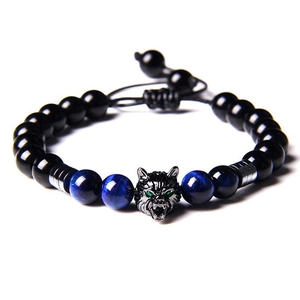 Detail of adjustable natural tiger eye and obsidian beads bracelet with a green-eyed wolf head