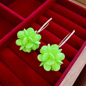 Vue macro des boucles d'oreilles boules de fleurs vert néon avec crochets dorés
