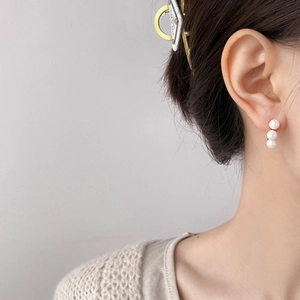 Detailed view of elegant triple vertical pearls earring on gold setting worn by model