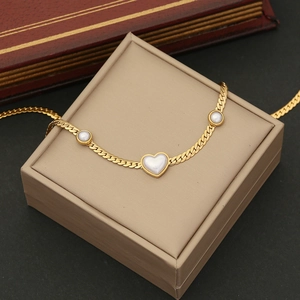 Detail of gold chain necklace featuring heart and round pearls on a jewelry box